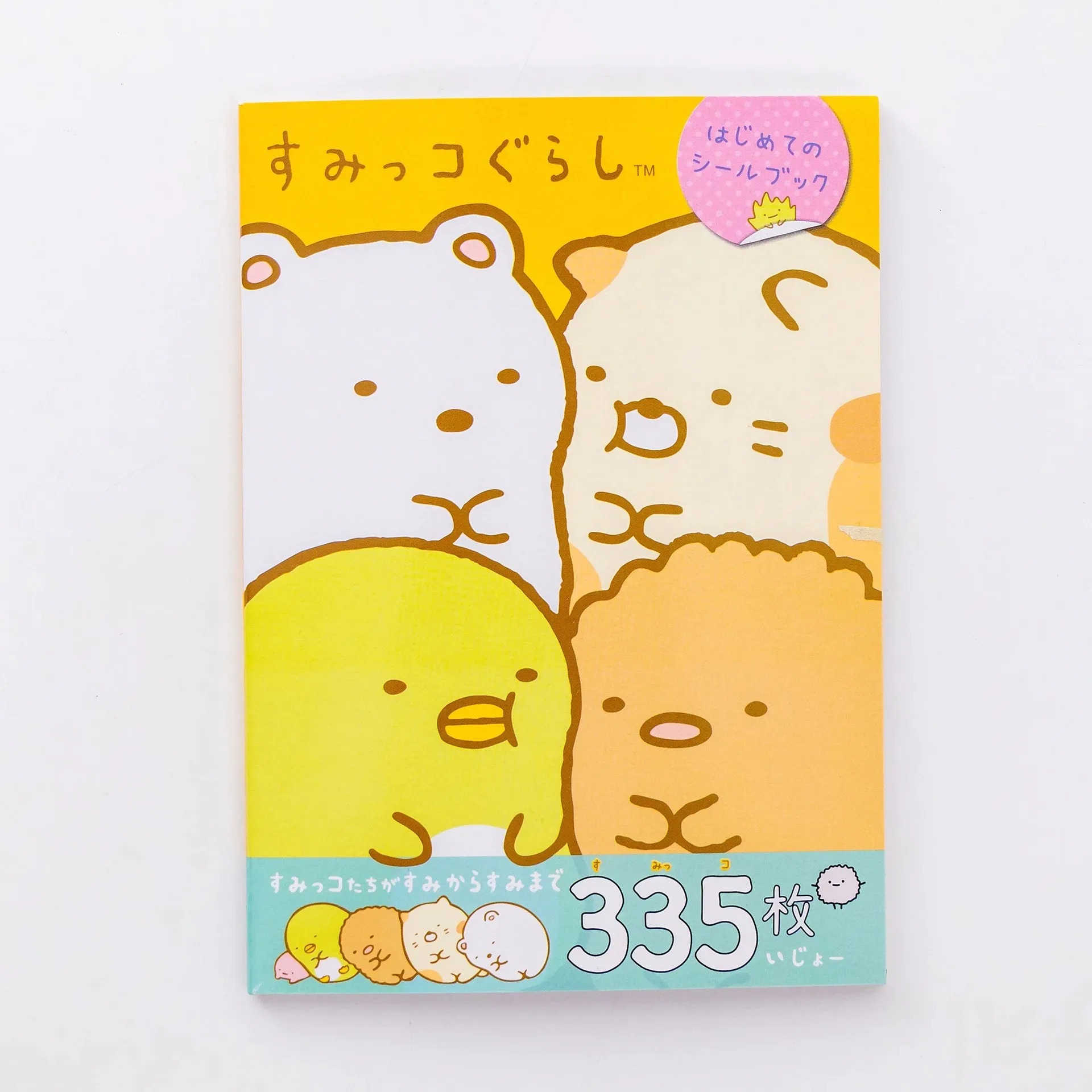 Capa do livro de adesivos do Sumikko Gurashi, da San-X, com Shirokuma e amigos sobre fundo amarelo e laranja