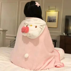 Pessoa de costas com a manta rosa de capuz da Hello Kitty, laço rosa e pompom, sentada numa cama