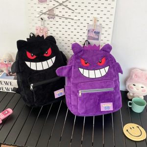 Duas mochilas felpudas do Gengar, de Pokémon, uma preta e outra roxa, sobre uma mesa