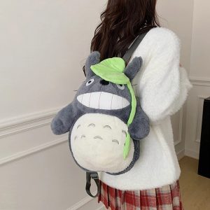 Mulher de costas com a mochila de pelúcia do Totoro e a folha verde