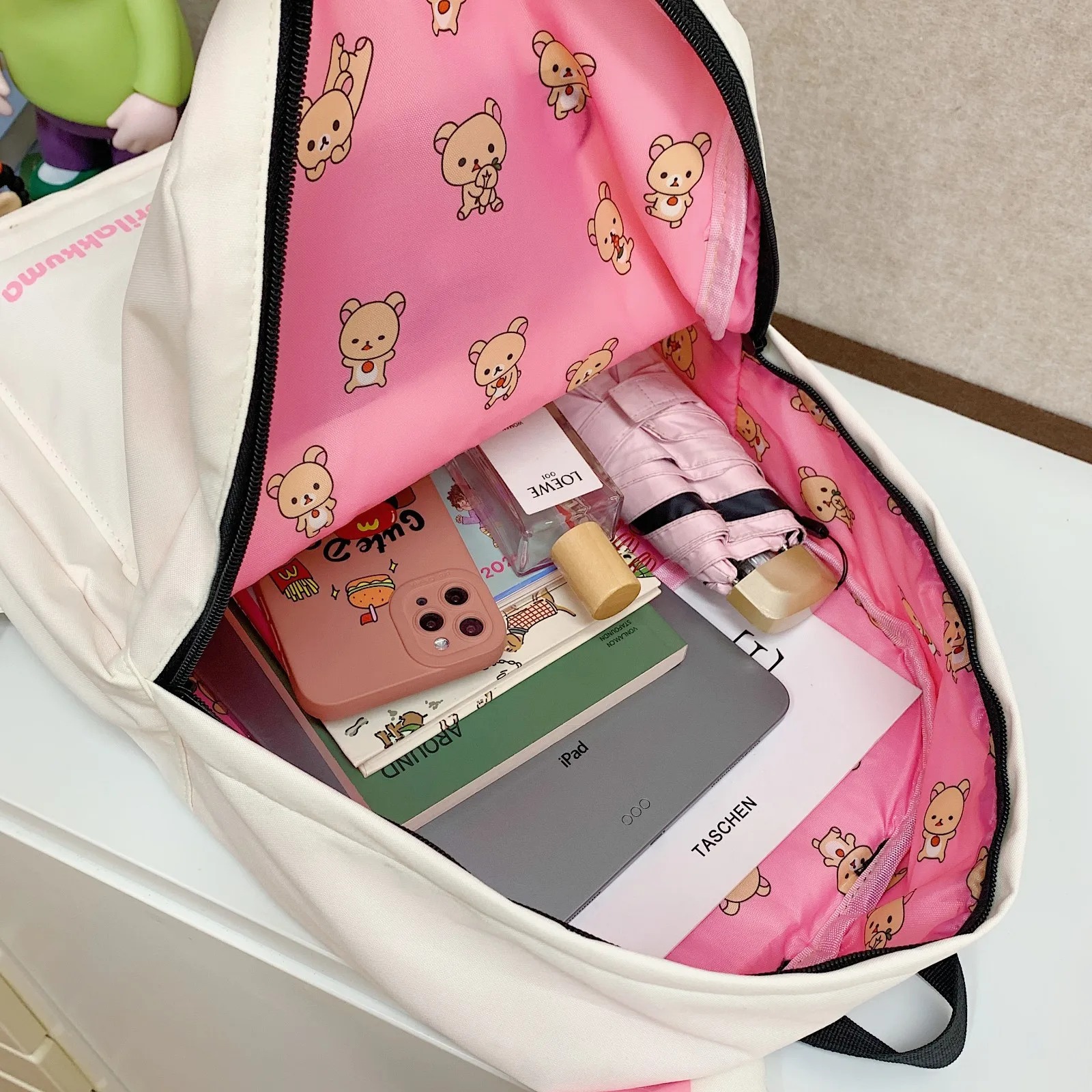 Por dentro da mochila do Rilakkuma: forro rosa com ursinhos e alguns objetos guardados