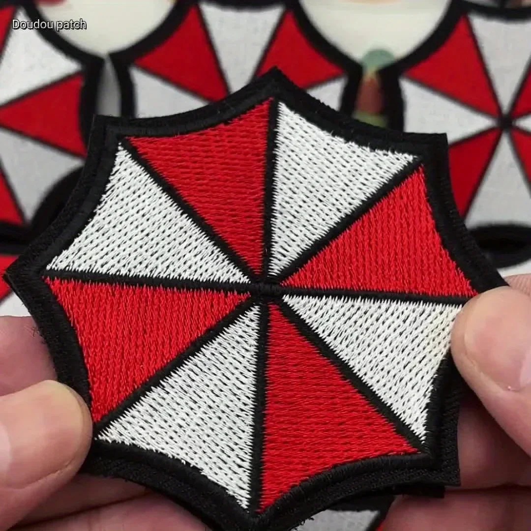 Bordado em relevo do patch Umbrella, de Resident Evil, segurado na mão