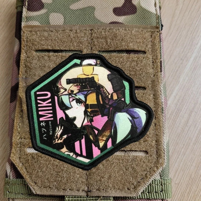 Patch da Hatsune Miku, de Vocaloid, preso num painel de velcro camuflado