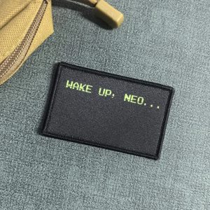 Patch preto com a frase Wake up, Neo... em verde, de Matrix, sobre fundo cinza