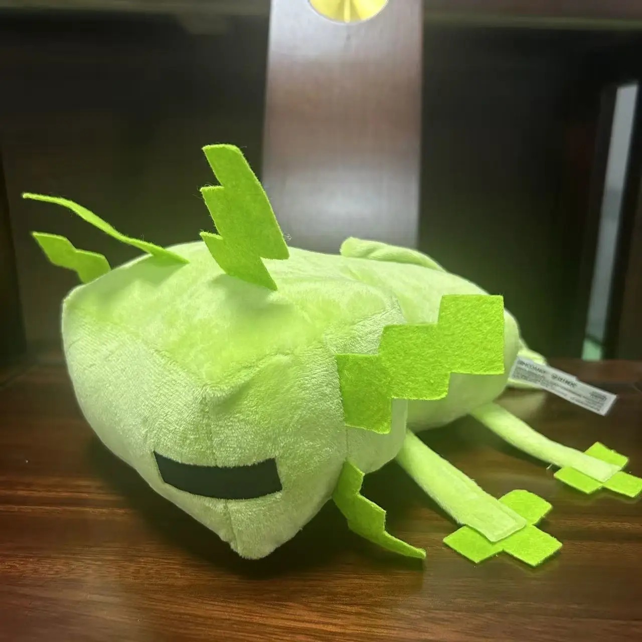 Axolote verde de Minecraft em pelúcia, de lado, com guelras e patas de feltro