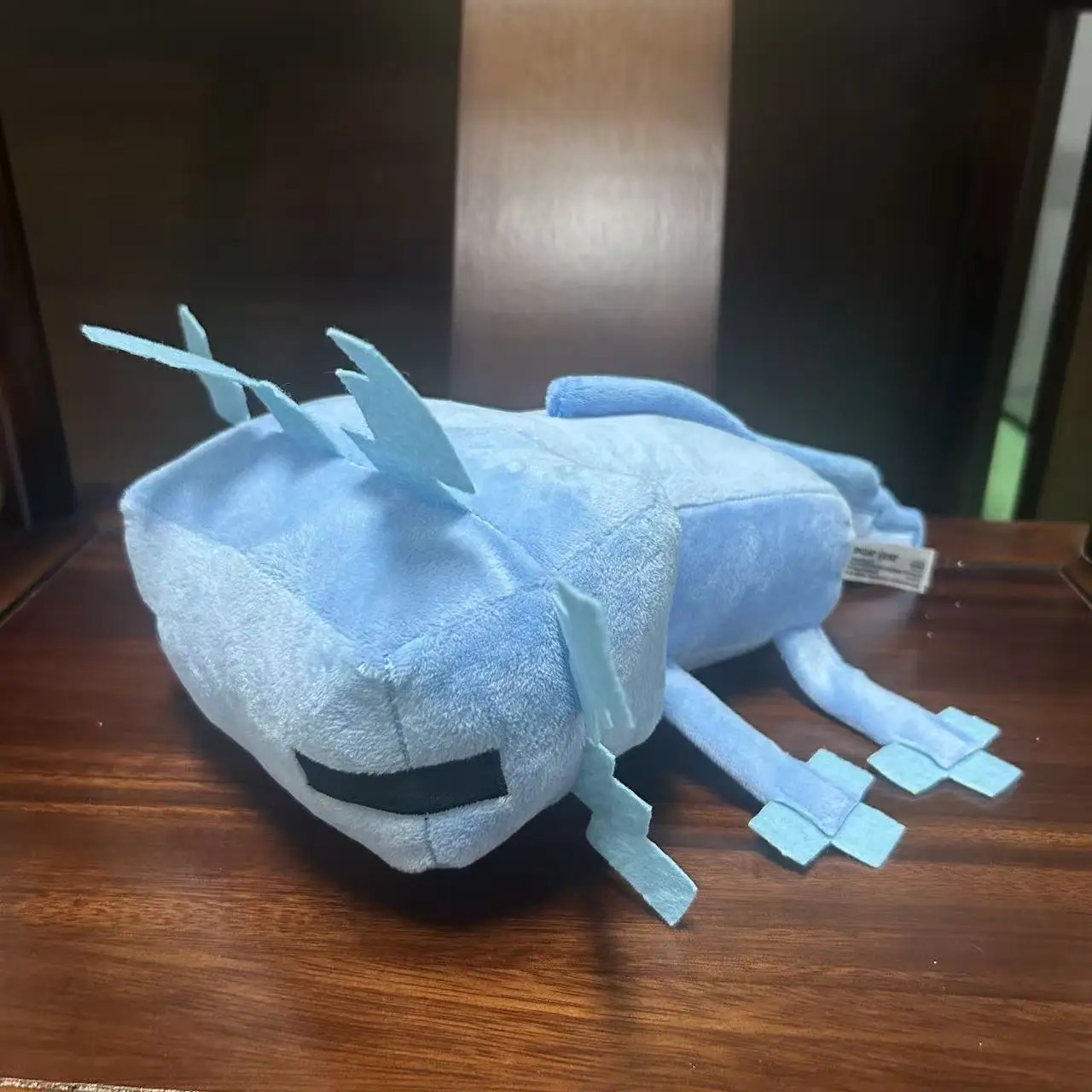 Axolote azul de Minecraft em pelúcia, deitado, com guelras claras