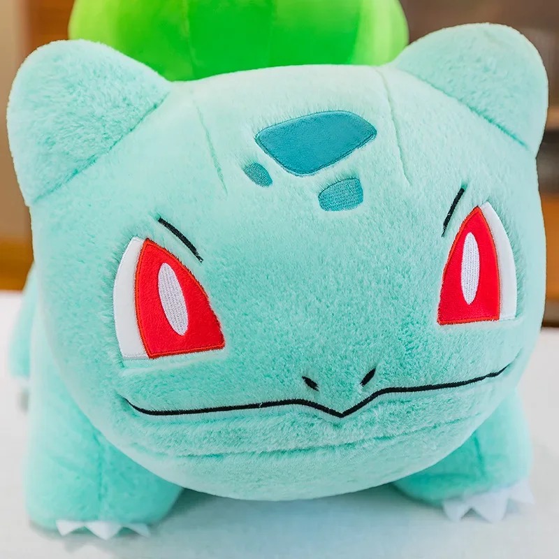 Rosto da pelúcia do Bulbasaur de perto, com olhos vermelhos bordados