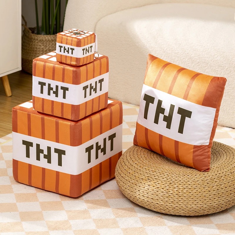 Cubos de pelúcia de TNT de Minecraft empilhados ao lado de uma almofada numa sala clara