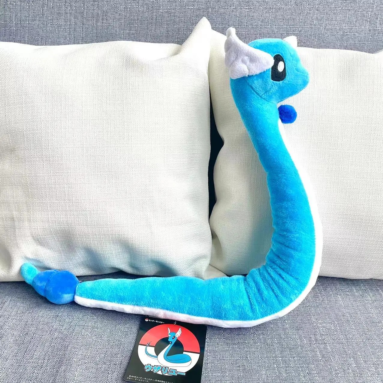 Dragonair de pelúcia, de Pokémon, com 65 a 70 cm, azul de barriga branca, sobre um sofá, com etiqueta