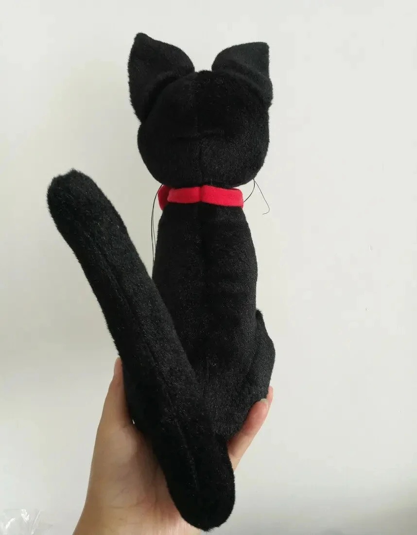 Pelúcia do Jiji vista por trás, com o rabo comprido e o laço vermelho