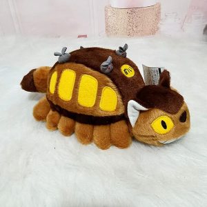 Gatobus de pelúcia, de Meu Amigo Totoro, sobre manta branca, de lado, com janelas amarelas e ratinhos