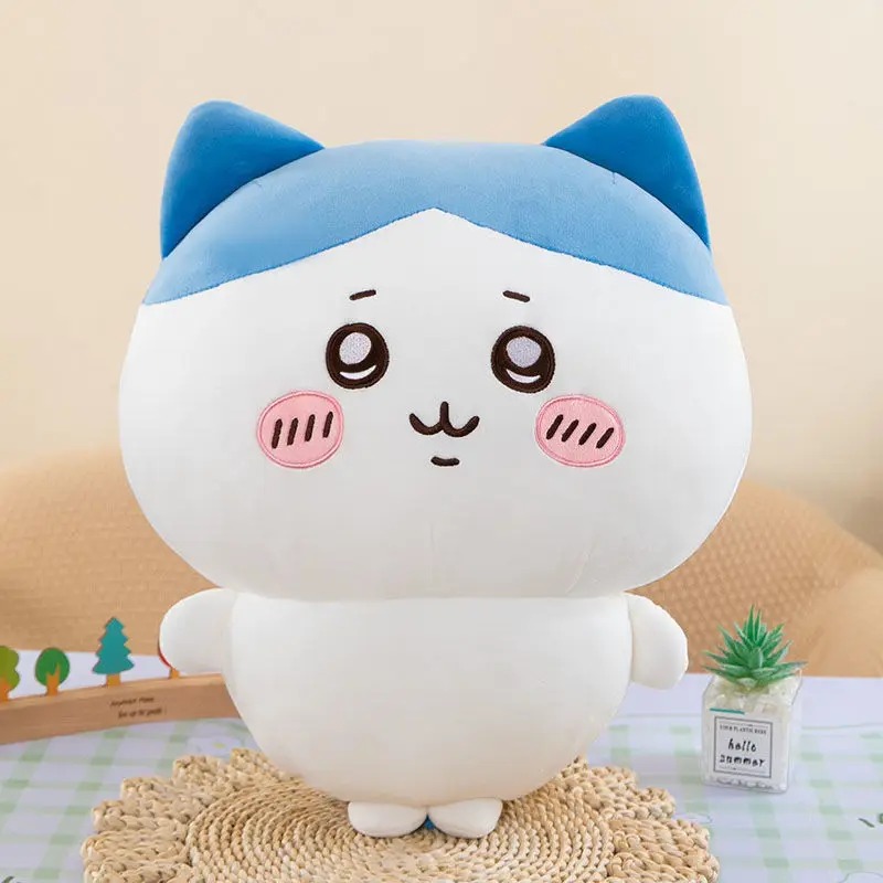 Hachiware de Chiikawa sentado sobre tapete de palha, gatinho branco com capuz azul