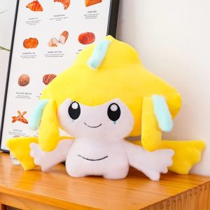 Jirachi de pelúcia, de Pokémon, amarelo e branco, com tiras azuis-claras, sobre uma mesa