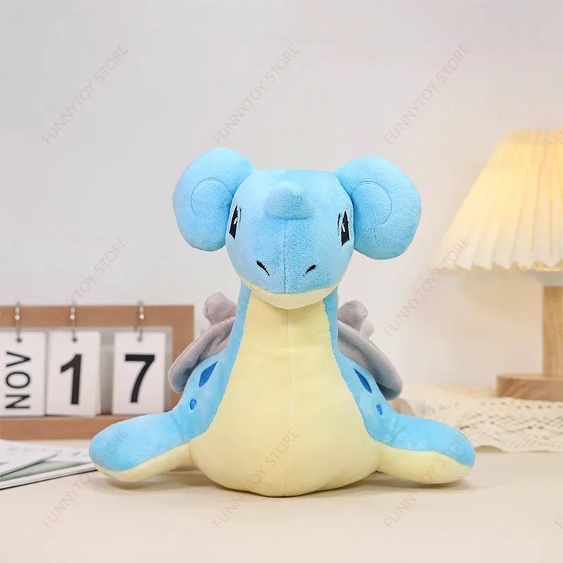 Lapras de Pokémon em pelúcia azul de barriga amarela, sentado sobre uma mesa