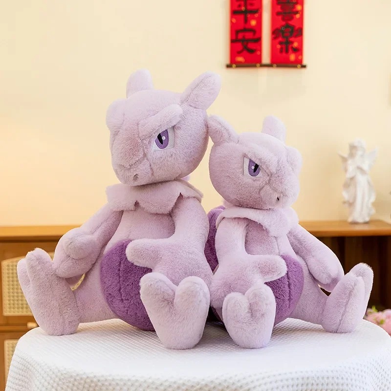 Duas pelúcias do Mewtwo sentadas lado a lado numa mesa