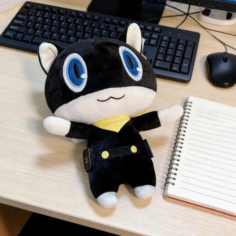 Pelúcia da Morgana, de Persona 5, sentada numa mesa ao lado de um caderno