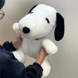 Pelúcia do Snoopy branca de orelhas pretas e coleira vermelha, nas mãos de uma pessoa