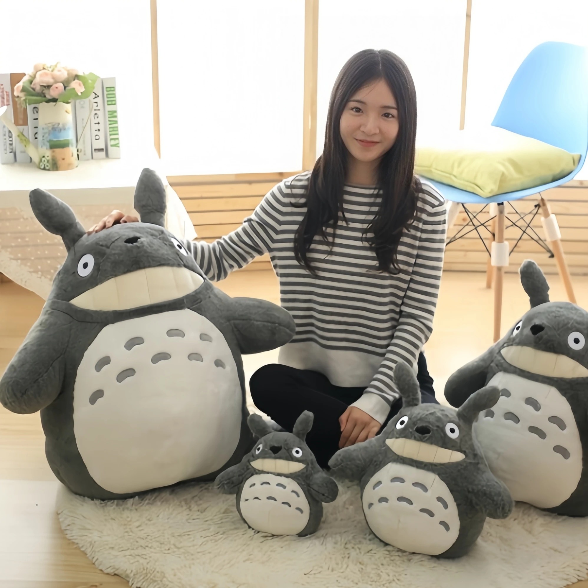 Pelúcias do Totoro nos quatro tamanhos ao lado de uma pessoa sentada, de Meu Amigo Totoro