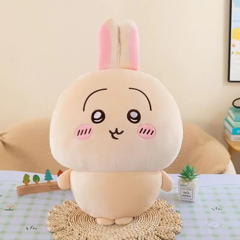 Usagi de Chiikawa, coelhinho de pelo bege e orelhas rosa, sentado sobre apoio de palha