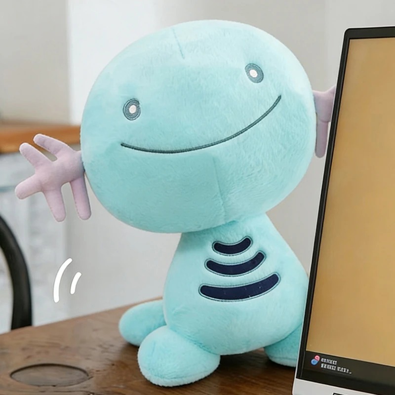 Wooper de pelúcia, de Pokémon, azul-turquesa, sentado numa mesa ao lado de um monitor