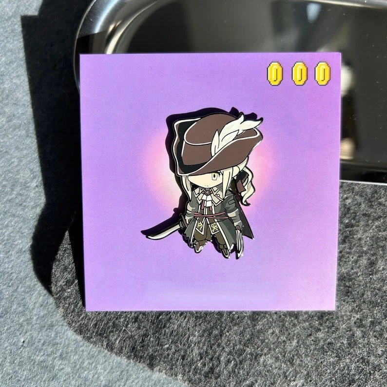Pin esmaltado chibi de Bloodborne, com personagem de chapéu de abas largas, sobre cartela roxa