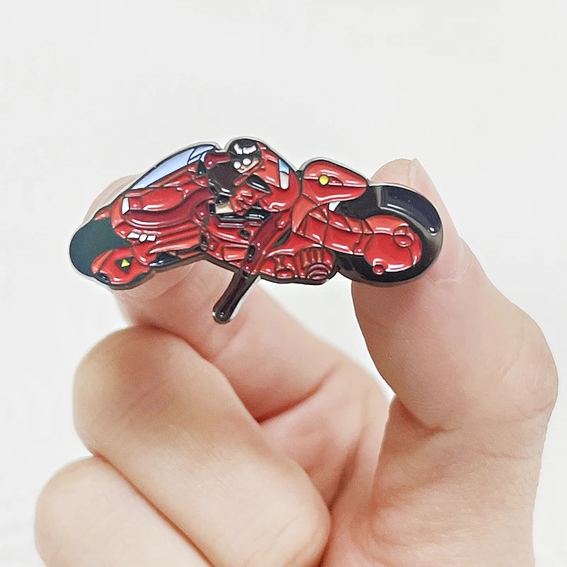 Pin da moto do Kaneda, de Akira, entre os dedos para mostrar o tamanho