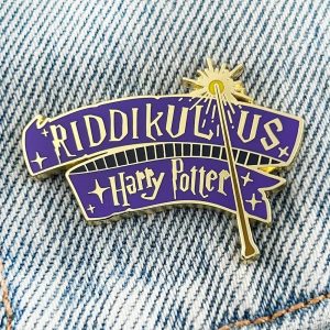 Pin esmaltado do feitiço Riddikulus, Harry Potter, em faixa roxa com varinha dourada, sobre jeans