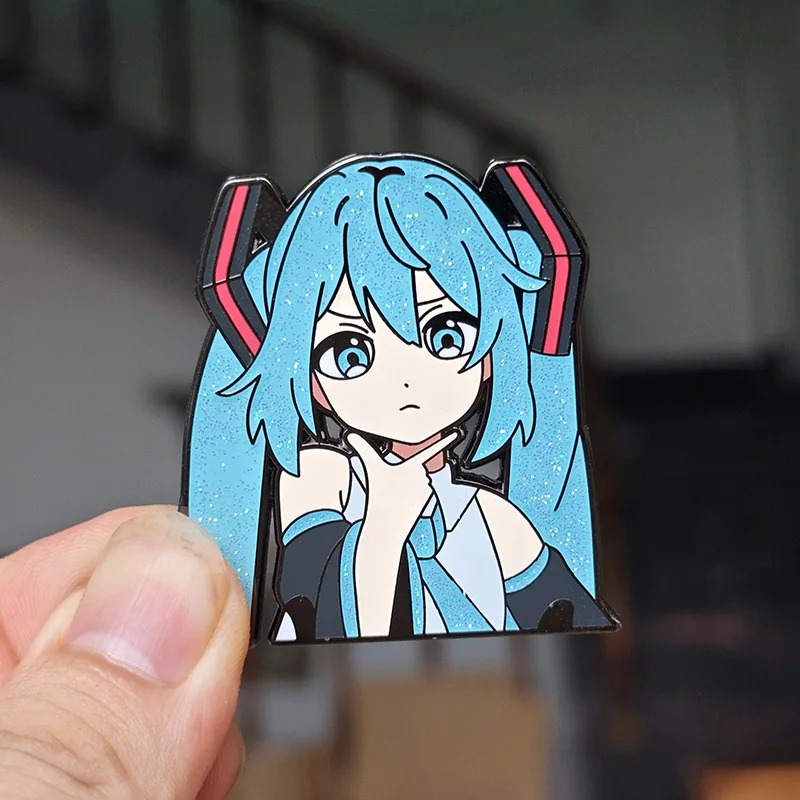 Pin da Hatsune Miku entre os dedos, para comparar o tamanho