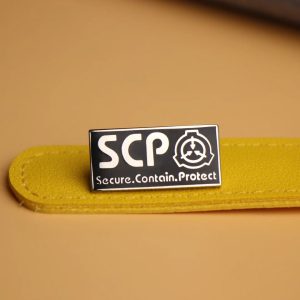 Pin esmaltado preto e branco com o logotipo da SCP Foundation sobre superfície amarela