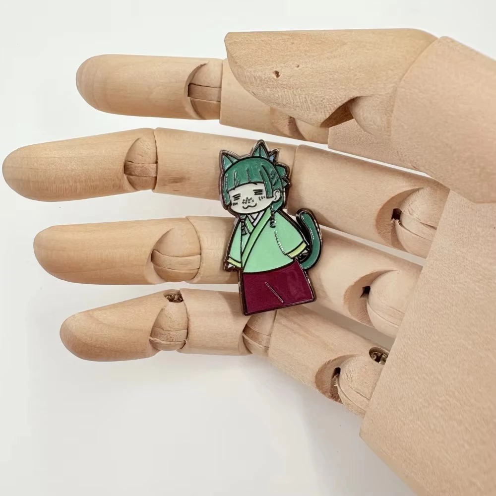 Pin esmaltado da Maomao chibi na mão de um manequim de madeira, para mostrar o tamanho