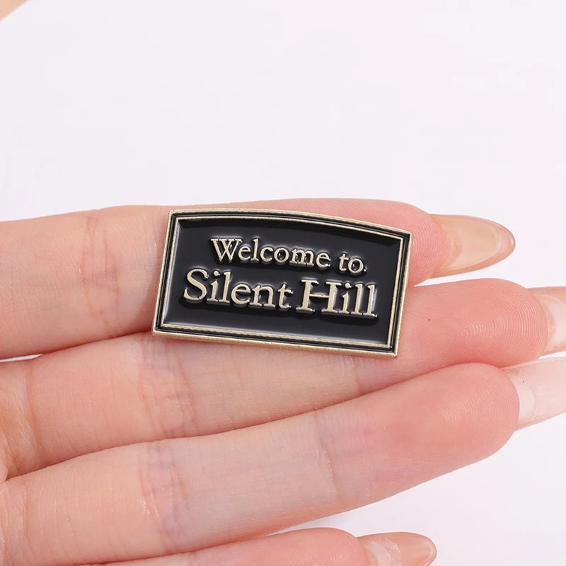 Pin Welcome to Silent Hill em esmalte preto, na palma de uma mão