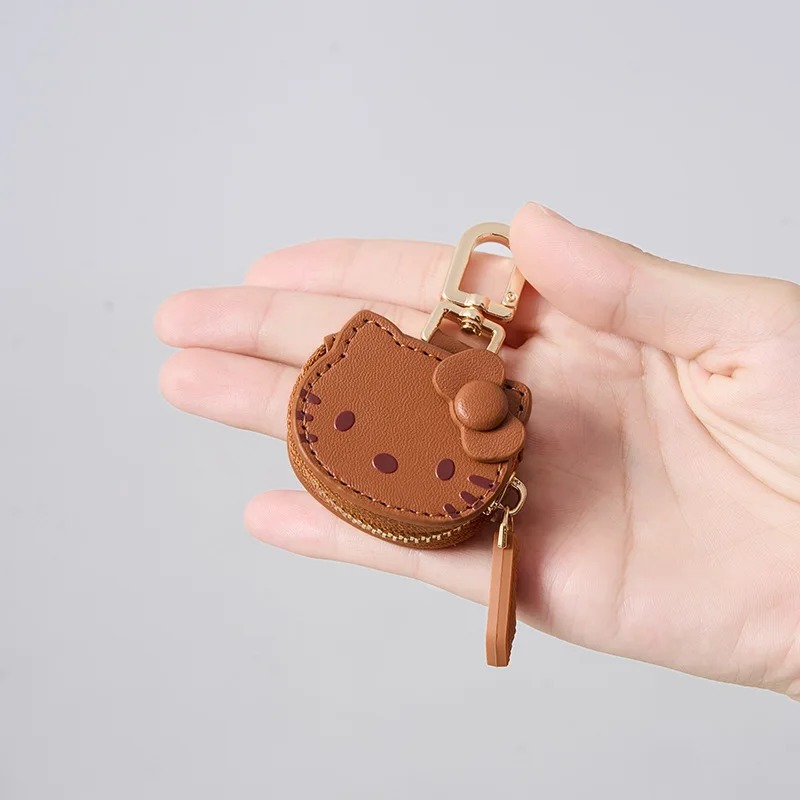 Mão segurando o porta-moedas marrom da Hello Kitty para mostrar o tamanho