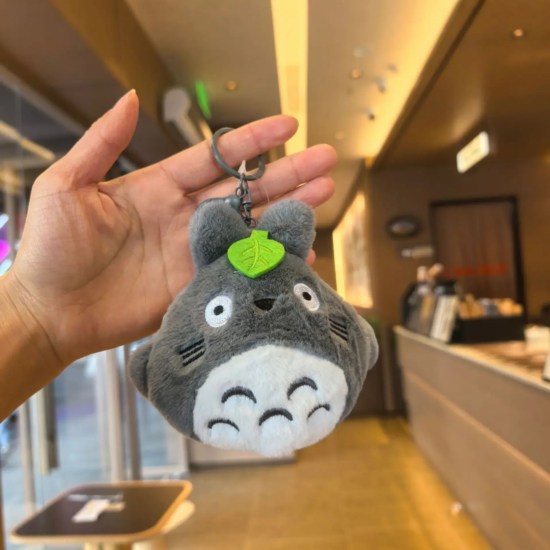 Porta-moedas de pelúcia do Totoro com argola de chaveiro, na mão