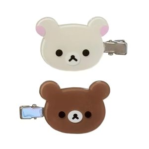 Presilhas do Rilakkuma, marrom, e da Korilakkuma, bege, com grampo de metal sobre fundo branco