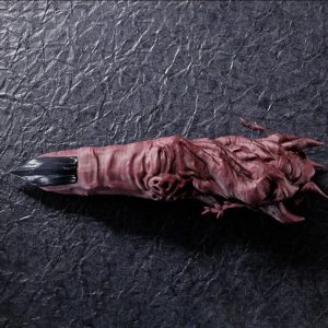 Dedo do Sukuna em PVC vermelho arroxeado e unha escura, sobre fundo cinza