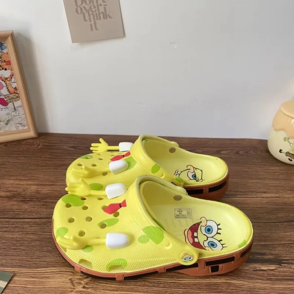 Tamancos amarelos do Bob Esponja com enfeites em relevo, sobre uma mesa de madeira