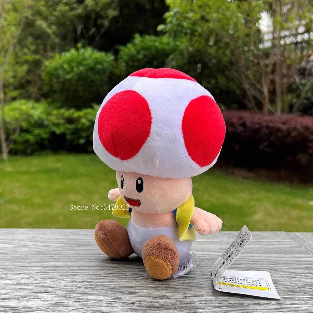 Toad de pelúcia de cogumelo vermelho com bolinhas, sentado sobre uma mesa