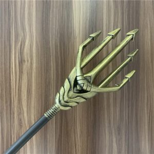 Cabeça dourada do tridente de cosplay com haste preta sobre fundo de madeira